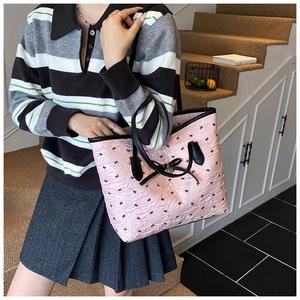Sac cabas rose à nœuds avec pendentif en cœur porté par un mannequin sous lumière douce