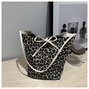 Detail of leopard print canvas tote bag featuring cream ribbon tie and woven texture