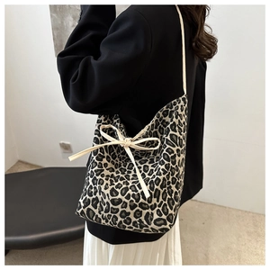 Detail of leopard print tote bag with a beige side ribbon bow on durable canvas texture