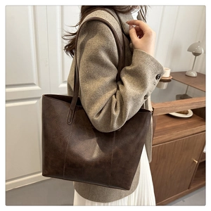 Vista detallada del bolso tote vintage marrón oscuro con textura de cuero mate y correa