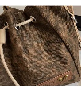 Close-up of leopard print canvas bucket bag with leather drawstring and butterfly charm
