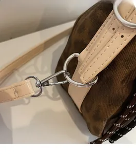 Detailed close-up of brown leopard print canvas with beige leather strap and silver D-ring