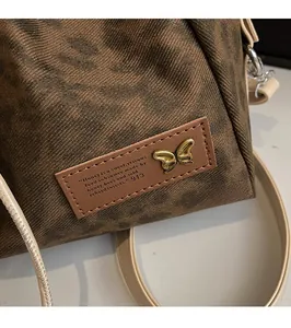 Detail of leopard print bucket bag with leather tag and gold butterfly metal hardware
