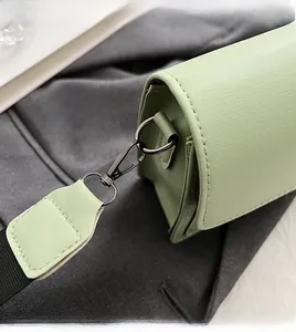 Detail of light green crossgrain leather bag with dark grey metal lobster clasp and strap