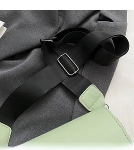 Detail of black nylon wide strap and silver metal buckle on a light green crossbody bag