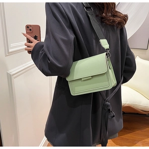 Chic mint green crossbody bag with a wide black shoulder strap shown on a model