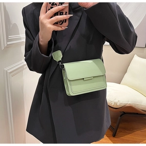 Close-up of mint green square bag with wide strap worn over a black blazer jacket