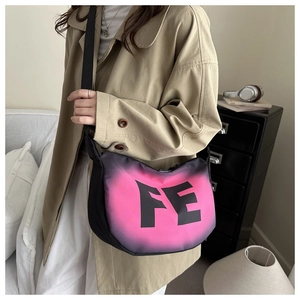 Detail of crossbody crescent bag featuring a pink gradient FE logo and wide strap