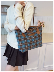 Detail of blue and brown checkered tote bag with leather straps and logo patch