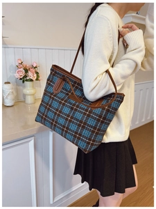 Close-up of vintage plaid tote bag with brown leather straps in a cozy indoor setting