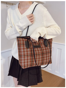 Detail of autumn plaid tote bag featuring orange tweed fabric and black leather handles