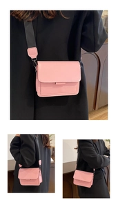 Detail of pink crossbody bag featuring wide woven strap and polished silver metal buckle