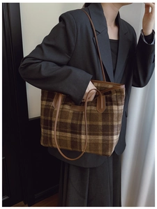 Détail du sac cabas à carreaux avec anses en cuir marron porté par un mannequin