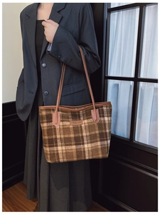 Detail of the brown plaid tote bag featuring a leather logo and vintage wool material
