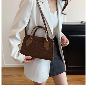 Détail d'un sac bowling imprimé léopard marron porté avec un blazer blanc chic