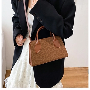 Detail of a brown leopard print tote bag with matte texture and sleek handle