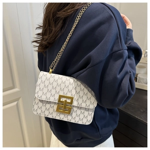 Close-up of golden metallic lock and grey M-letter print on the white crossbody bag