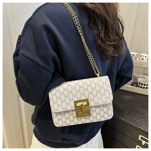 Detail view of a white leather chain bag with grey M-letter pattern and gold buckle