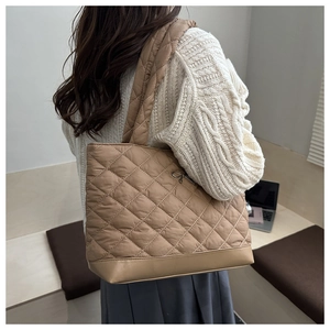 Brown quilted tote bag with diamond pattern shown on model for size and style reference