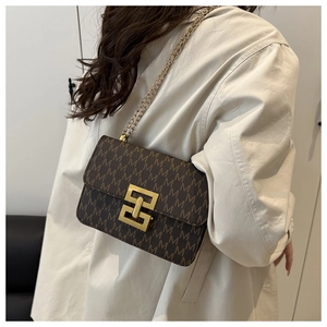 Detailed view of vintage monogram cross-body bag with golden interlocking clasp on model