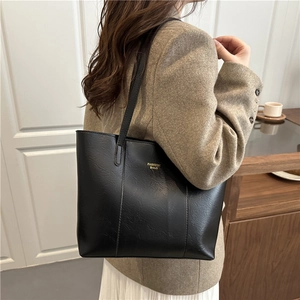 Sac fourre-tout chic en similicuir noir avec lettrage doré porté à l'épaule par un mannequin