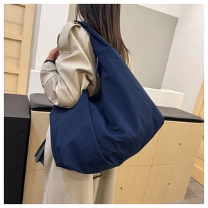 Model trägt eine große marineblaue Nylon-Umhängetasche in Halbmondform in der Seitenansicht