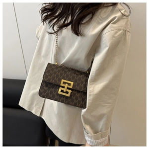 Vue détaillée du sac bandoulière marron avec monogramme, chaîne dorée et fermoir chic