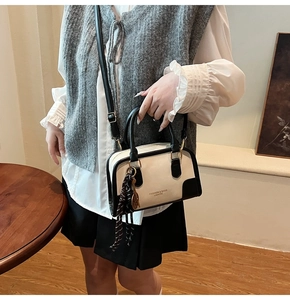Detail of a black and white contrast retro pillow bag with scarf pendant and shoulder strap