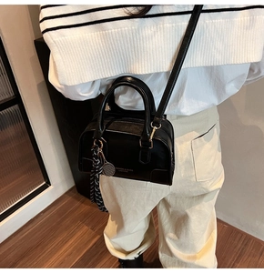 Vista laterale di una borsa Boston nera con ciondolo a racchetta indossata da modella