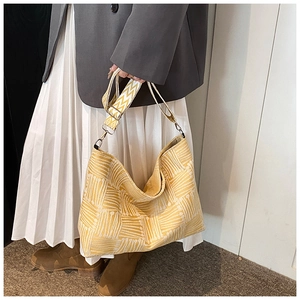 Detailed view of yellow woven tote bag with wide textured strap and geometric pattern