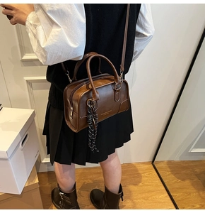 Dettaglio della borsa Boston vintage marrone con testo dorato e ciondolo in seta chic
