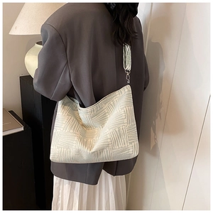 Detail of light green jacquard tote bag with textured stripes and silver metal buckle