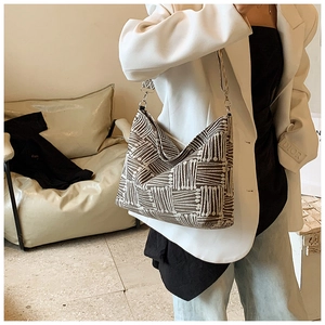 Detail of striped canvas tote bag showing textured geometric pattern and embroidered strap