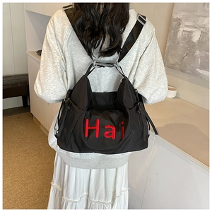 Detail of red Hai embroidery on black nylon backpack shown on model back
