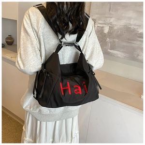 Detail of black nylon travel bag featuring red 'Hai' embroidery and adjustable strap