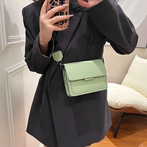 Mint green square crossbody bag with wide strap shown on a model in a black blazer