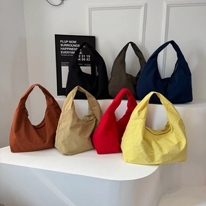 Sammlung von minimalistischen Hobo-Schultertaschen in sieben Farben auf weißen Stufen