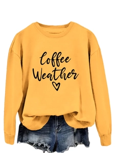 Close-up of mustard yellow sweatshirt with Coffee Weather text and heart print detail