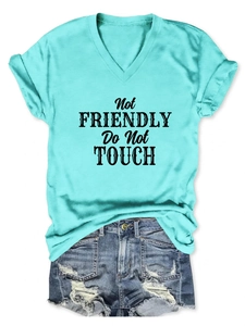 Detail of turquoise V-neck T-shirt with black Not Friendly slogan and ripped denim shorts