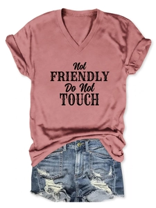 Close-up of pink V-neck t-shirt with 'Not FRIENDLY Do Not TOUCH' text and ripped denim shorts