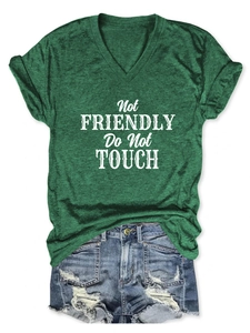 Flat lay of a green V-neck T-shirt with 'Not Friendly' print and denim shorts outfit