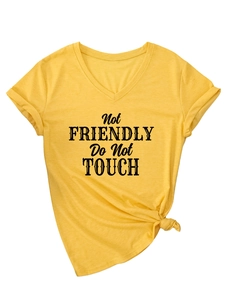 Detail of V-neck yellow tee featuring black Not Friendly text and knotted side hem