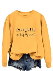 Détail du sweat jaune avec texte fearfully wonderfully made et col rond côtelé