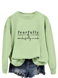 Détail d'un sweat vert menthe avec texte graphique noir Fearfully Wonderfully Made