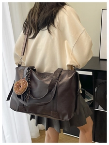 Close-up of retro brown faux leather tote bag with wide strap and donut charm detail