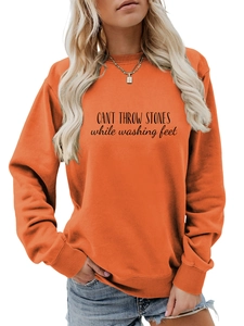 Détail du sweat-shirt orange vif avec impression de texte noir sur la poitrine