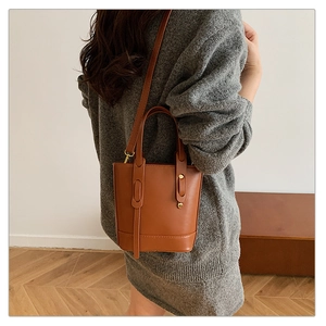 Detail of brown leather bucket bag with handle and strap shown in a lifestyle setting