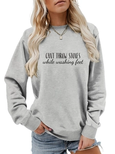 Détail du sweat-shirt gris avec texte artistique noir 'CAN'T THROW STONES' imprimé