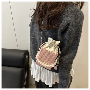 Détail du sac seau rose tressé avec poignée en perles et doublure à cordon blanc