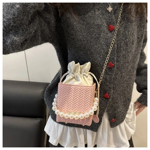 Close-up of pink woven bucket bag featuring a pearl handle and satin drawstring pouch